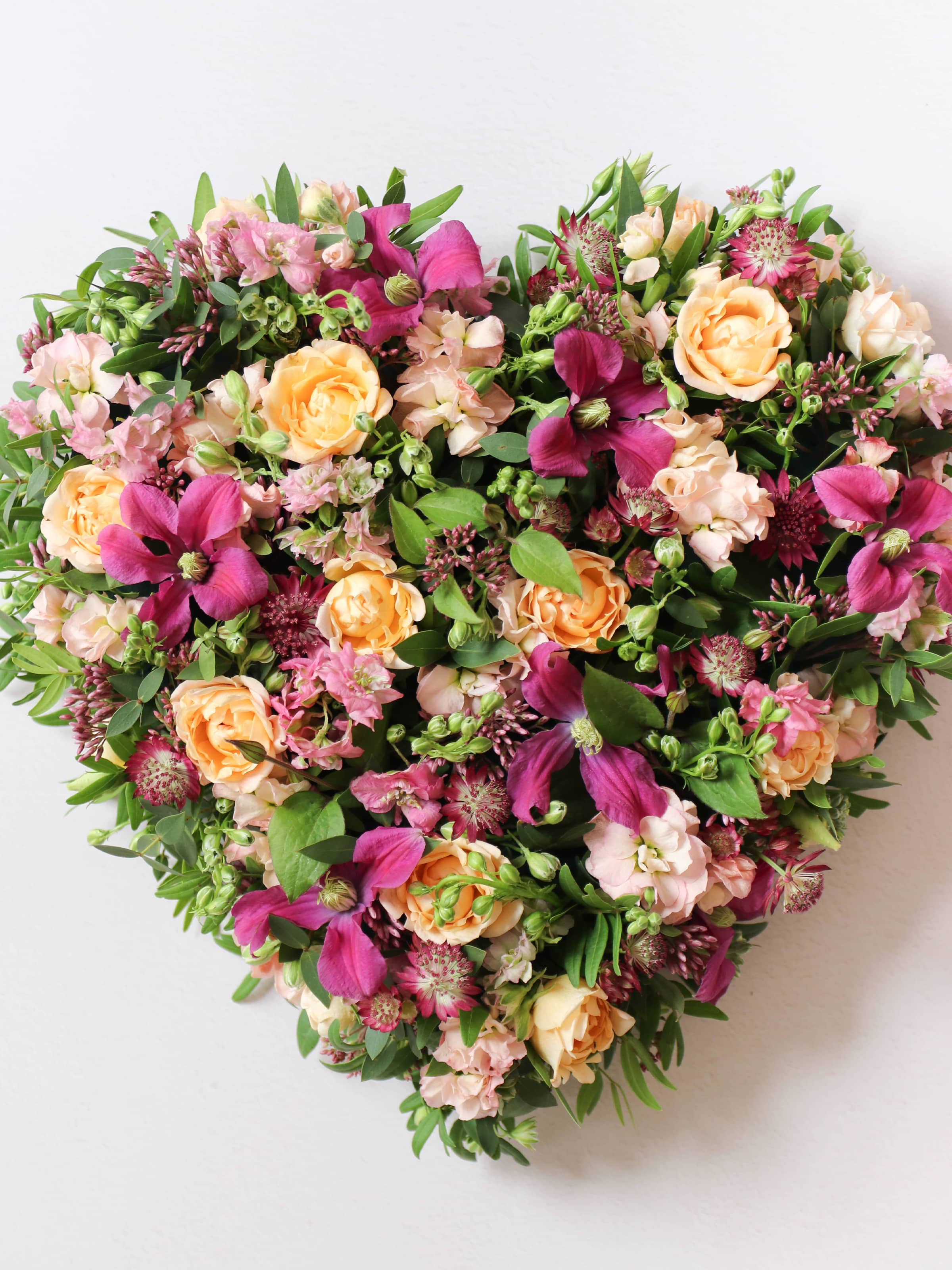 Heart-shaped posy with bright pink and peach flowers on a white background