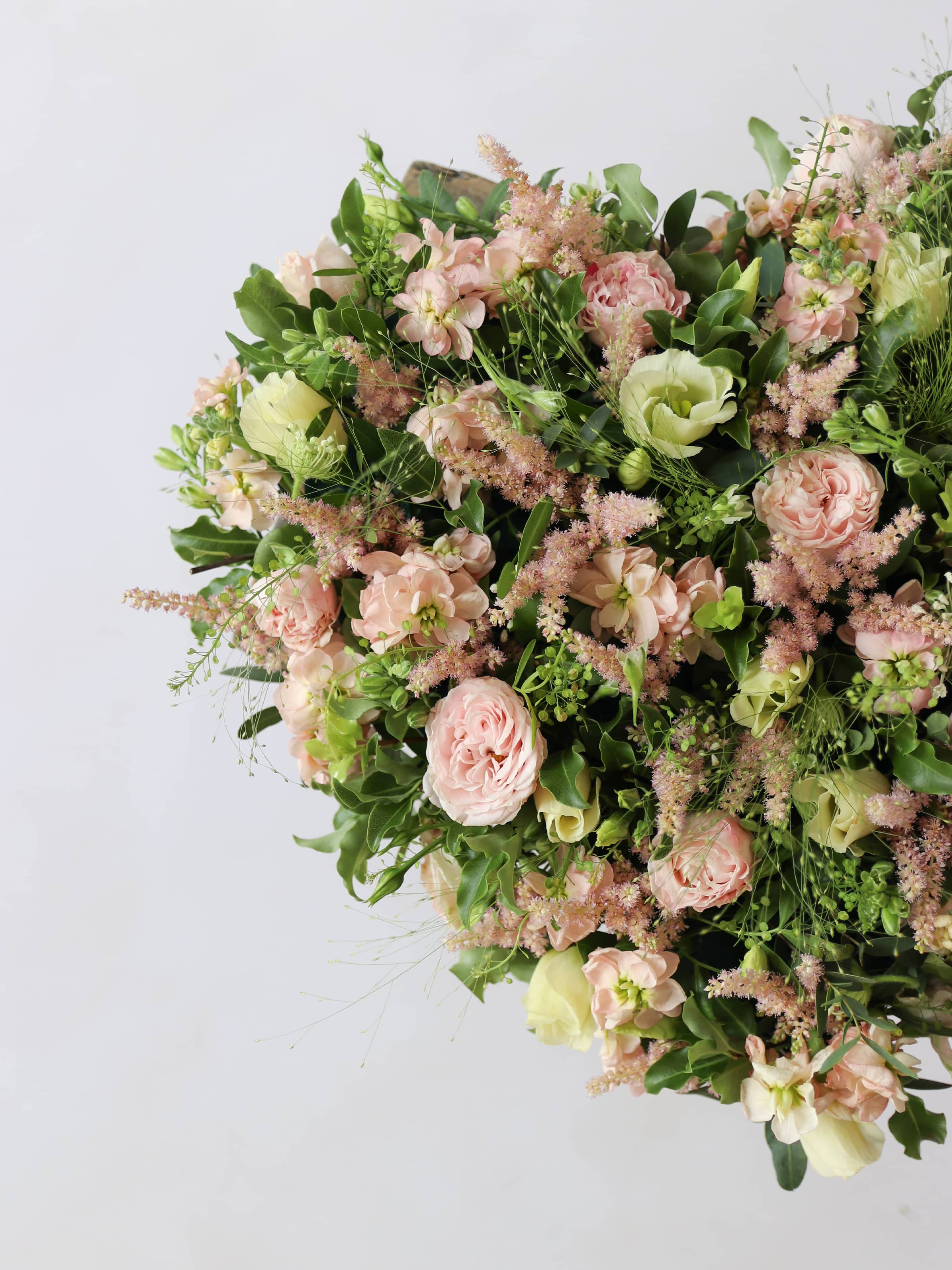Heart shaped funeral posy with pink and green colours on a white background
