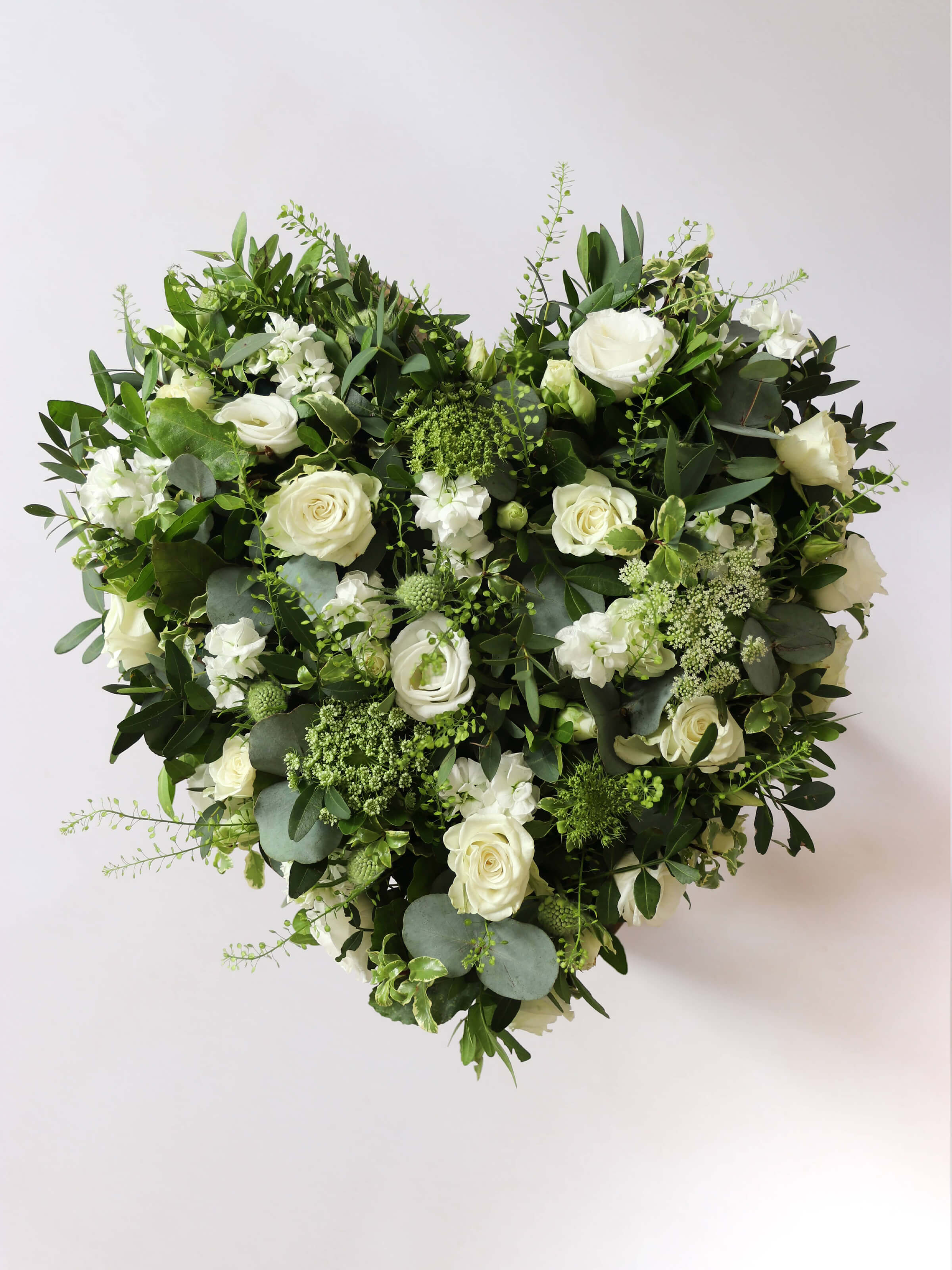 Heart shaped funeral posy with white and green flowers on a white background