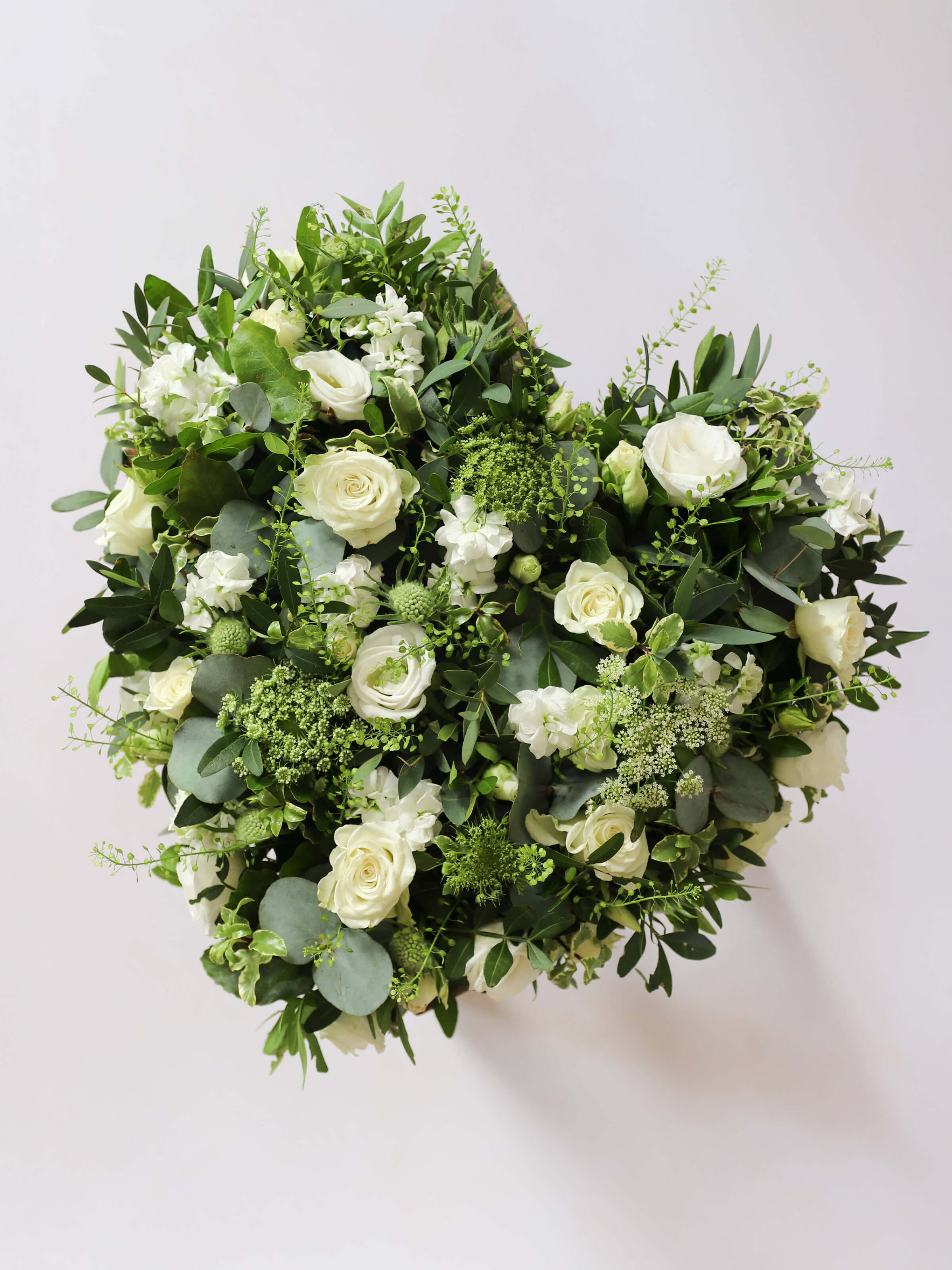 Heart shaped funeral posy with white and green flowers on a white background
